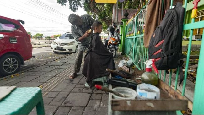 Udin memulai usaha jasa cukur rambut di bawah pohon rindang di kawasan Alun-Alun Utara, Kota Yogyakarta, sejak tahun 2002 lalu.