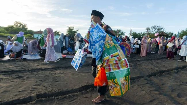 Penjual asongan menjajakan tikar plastik dagangannya kepada para jemaah salat Idulfitri 1446 Hijriyah di Gumuk Pasir Parangtritis, Bantul, Daerah Istimewa Yogyakarta, Senin (31/3/2025).