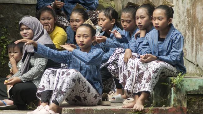 Sejumlah anak perempuan menyaksikan tari-tarian yang ditampilkan dalam kegiatan Merti Mbelik, di Tepi Sungai Winongo, Kampung Badran, Bumijo, Kecamatan Jetis, Kota Yogyakarta, Kamis (10/7/2025).